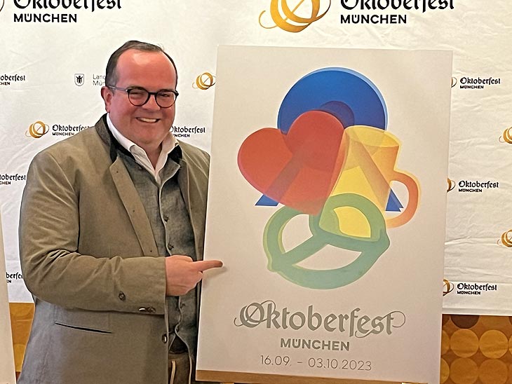 Clemens Baumgärtner, Vorsitzender der Plakatjury und Referent für Arbeit und Wirtschaft, mit dem Wiesnplakat 2023 von Manfred Escher, 1. Preis im Plakatwettbewerb (©Foto.Martin Schmitz)